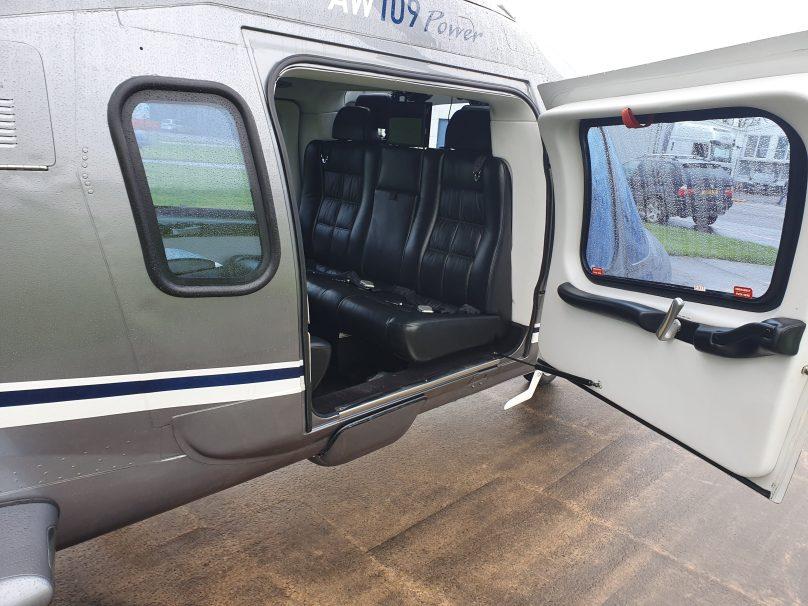 Black leather seats and large windows inside the cabin of a twin-engine charter helicopter