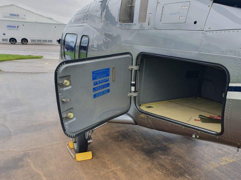 Open luggage hold door of an Agusta 109 Grand helicopter showing the baggage space
