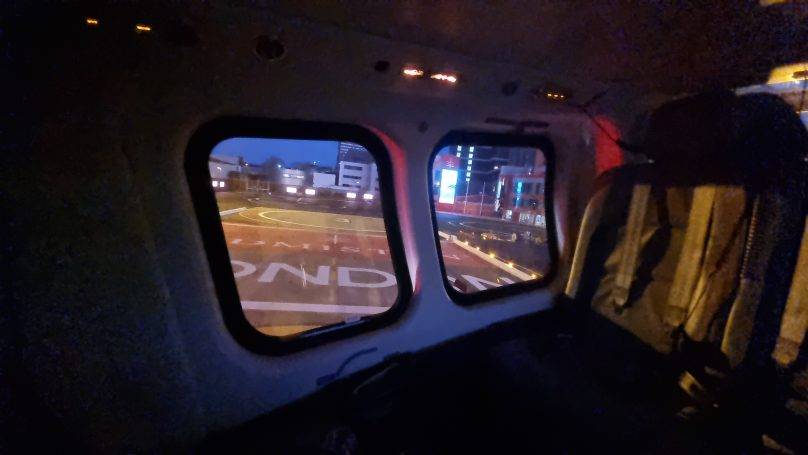 Inside a helicopter cabin at night with city lights through the windows