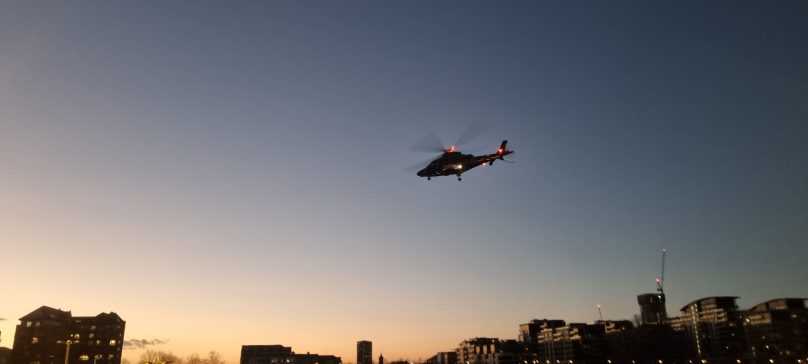 Helicopter taking off from London into a darkening dusk sky