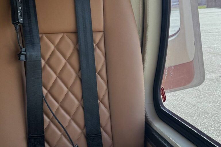 Tan leather seats and seat belts inside a charter helicopter cabin
